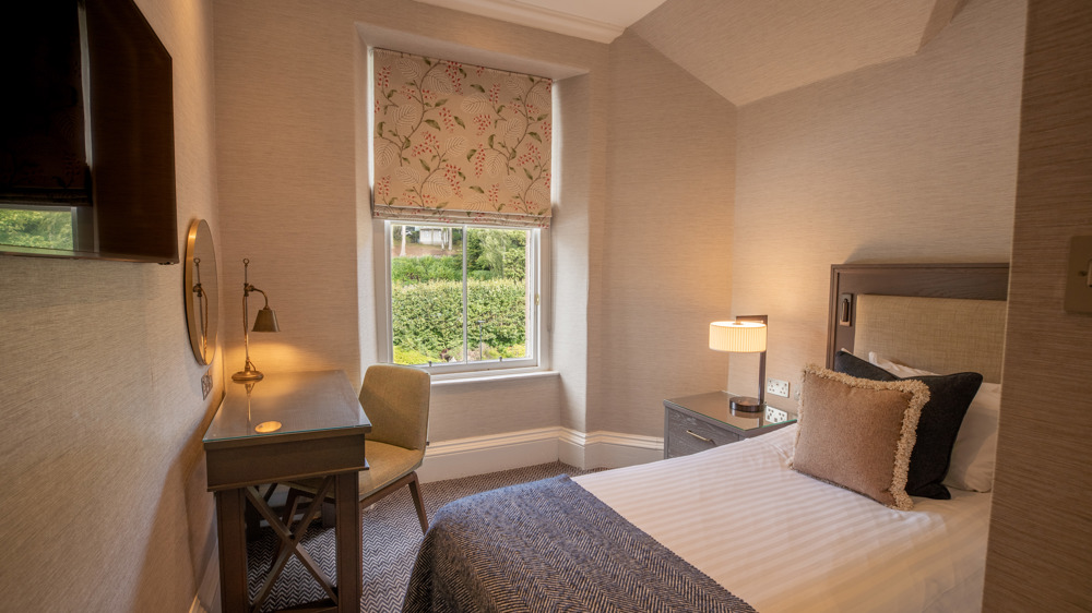 Guest single room with single bed, desk, and TV.