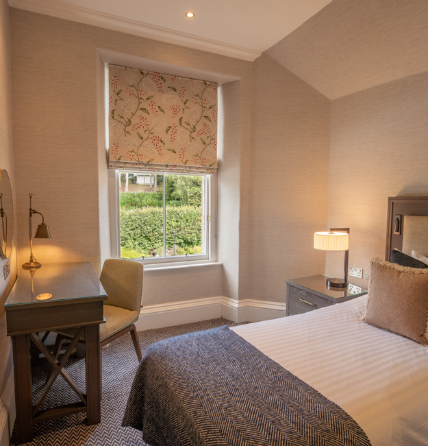 Guest single room with single bed, desk, and TV.