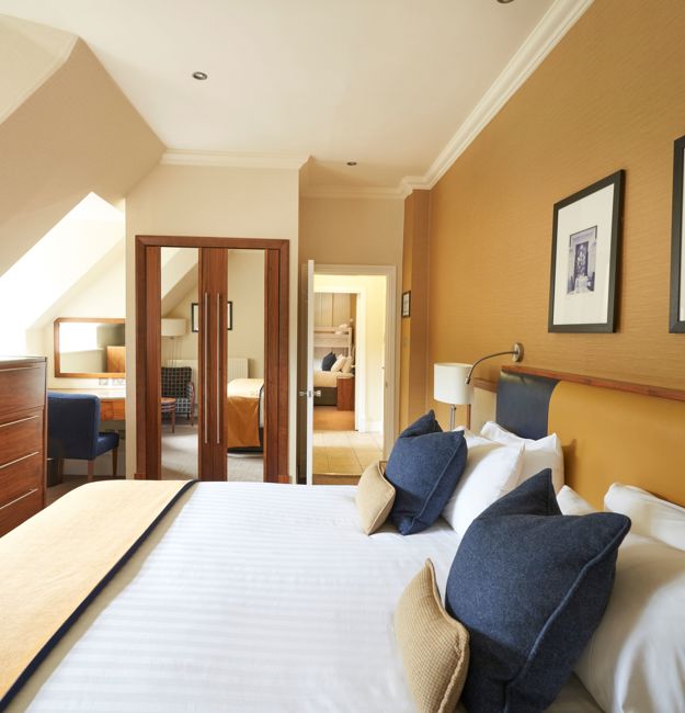 Family apartment with king-sized bed, dresser, TV. You can see the other sleeping area in the background.