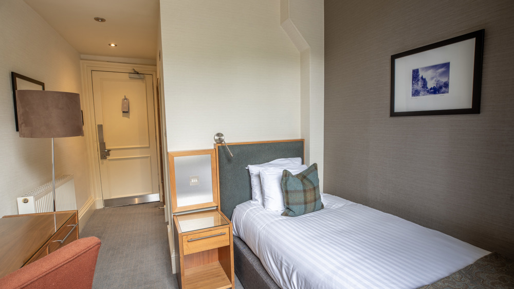 Guest single room with single bed, bedside table, and desk.