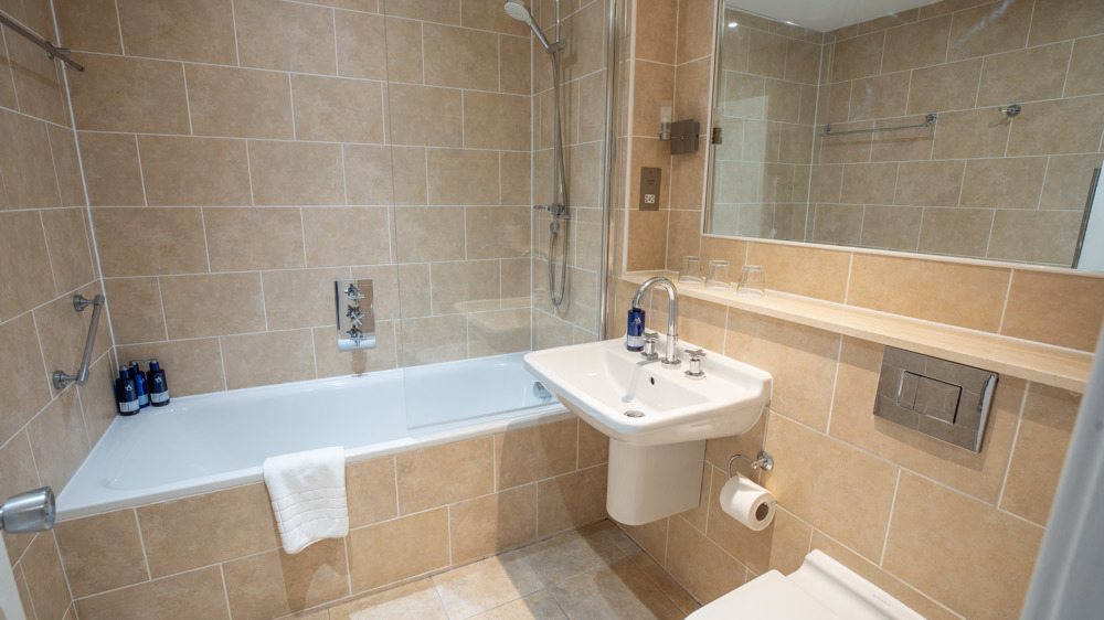 Bathroom with shower over bath, sink, toilet, and mirror.