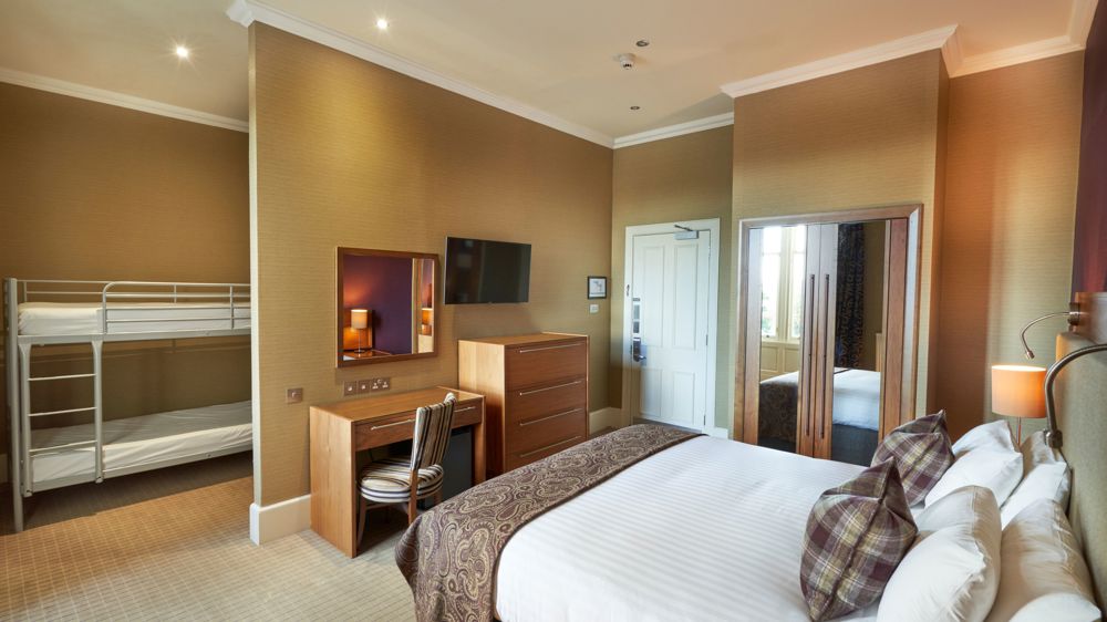 Room with king-sized bed, vanity, TV, dresser, and bunk beds partially behind a wall