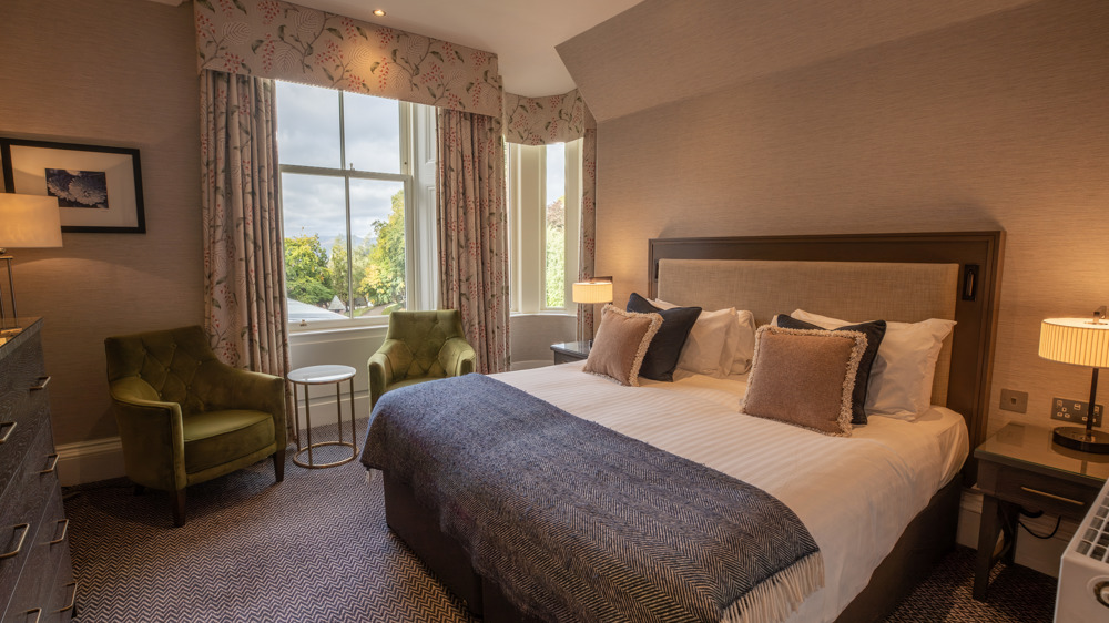 Guest Double room with king-sized bed, bedside table, two chairs, and a window.