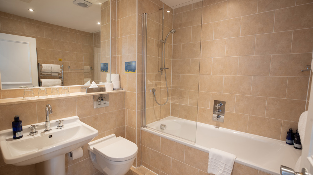 Bathroom with shower over bath, toilet, sink and mirror