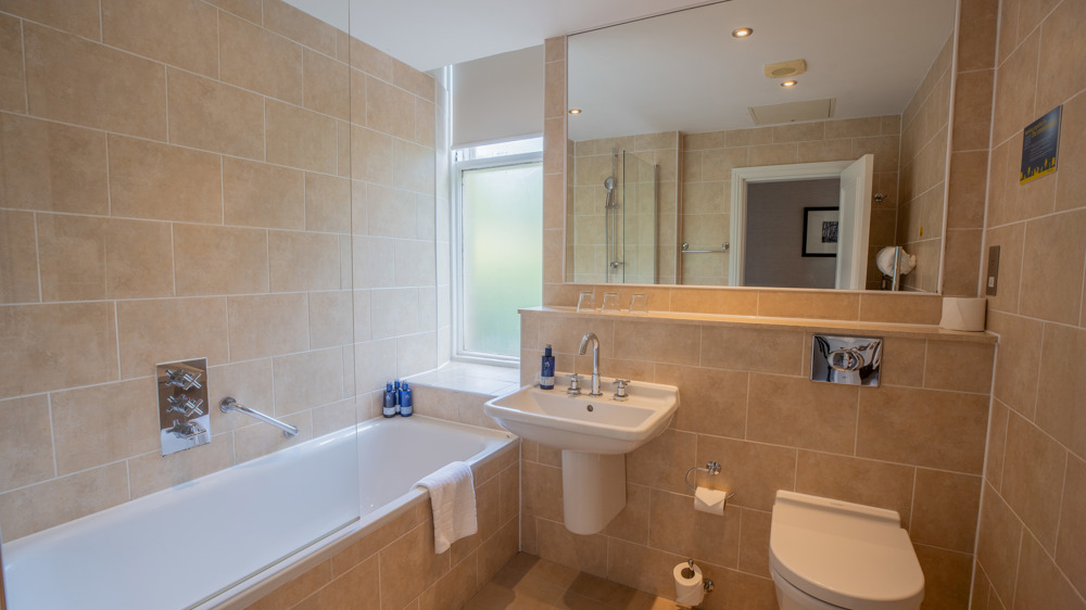 Bathroom with a bathtub, a sink, a mirror, and a toilet.